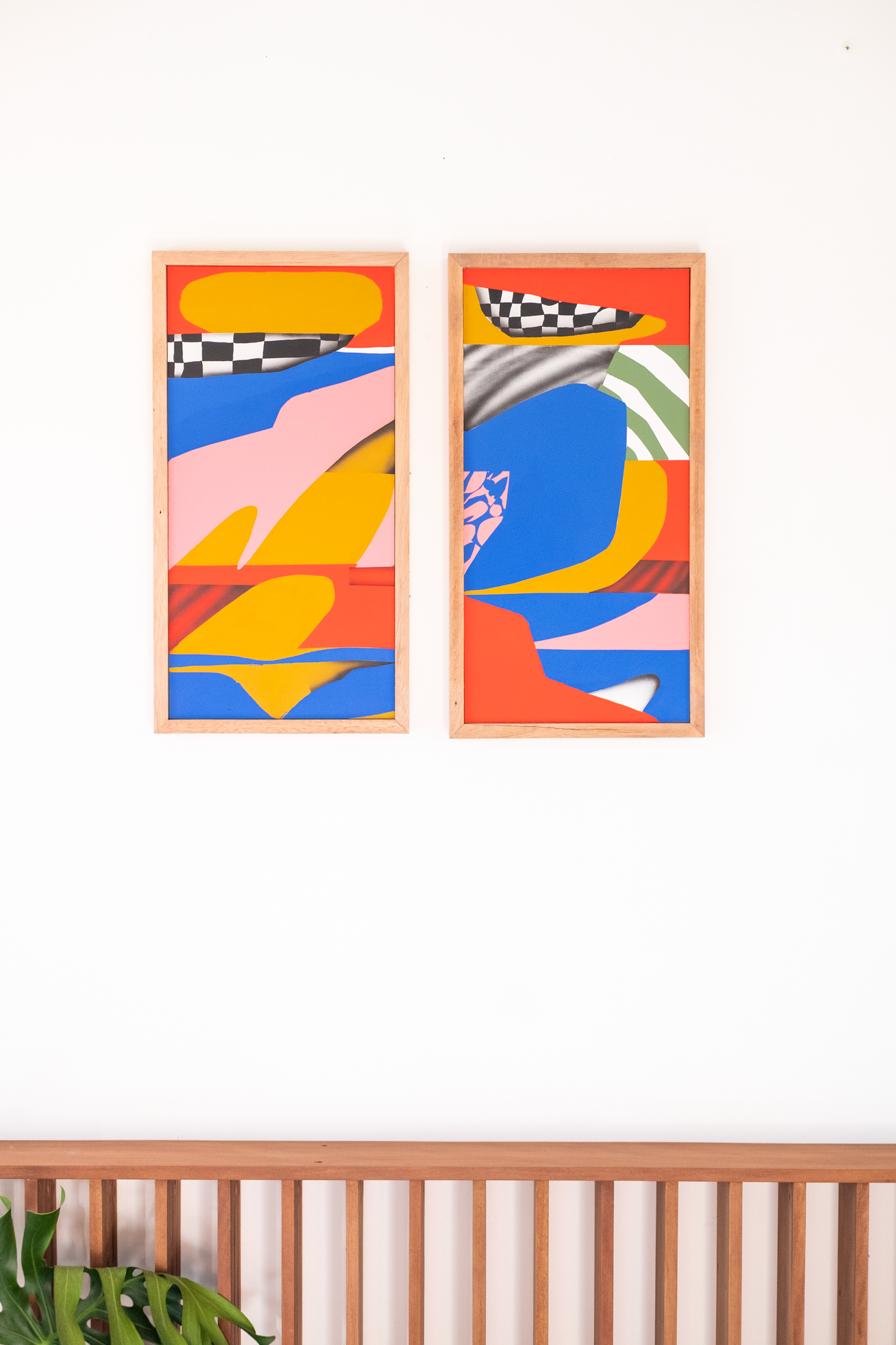 Two abstract art pieces in wooden frames on a white wall.