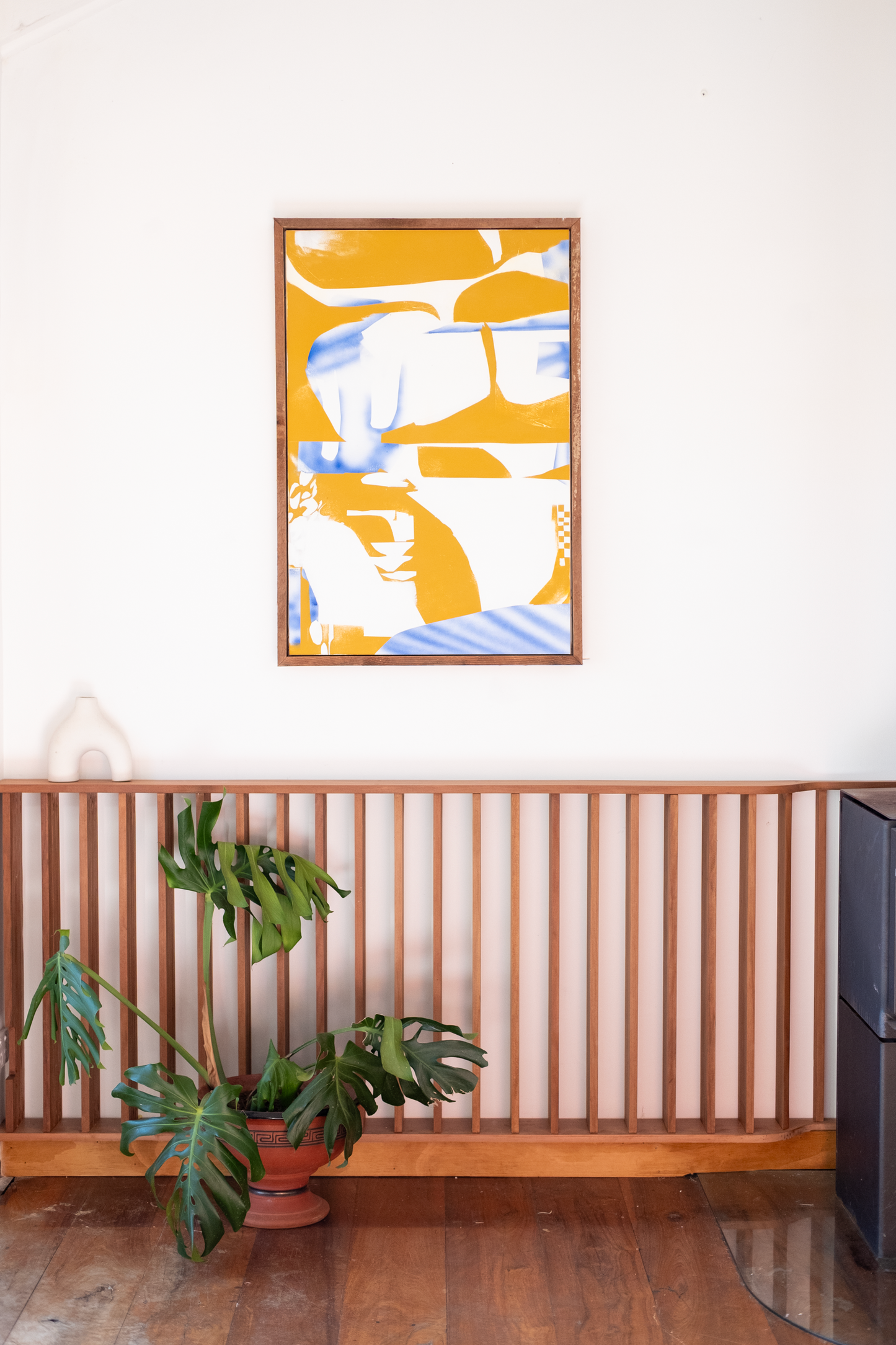 Abstract art piece on a wall above a plant and radiator