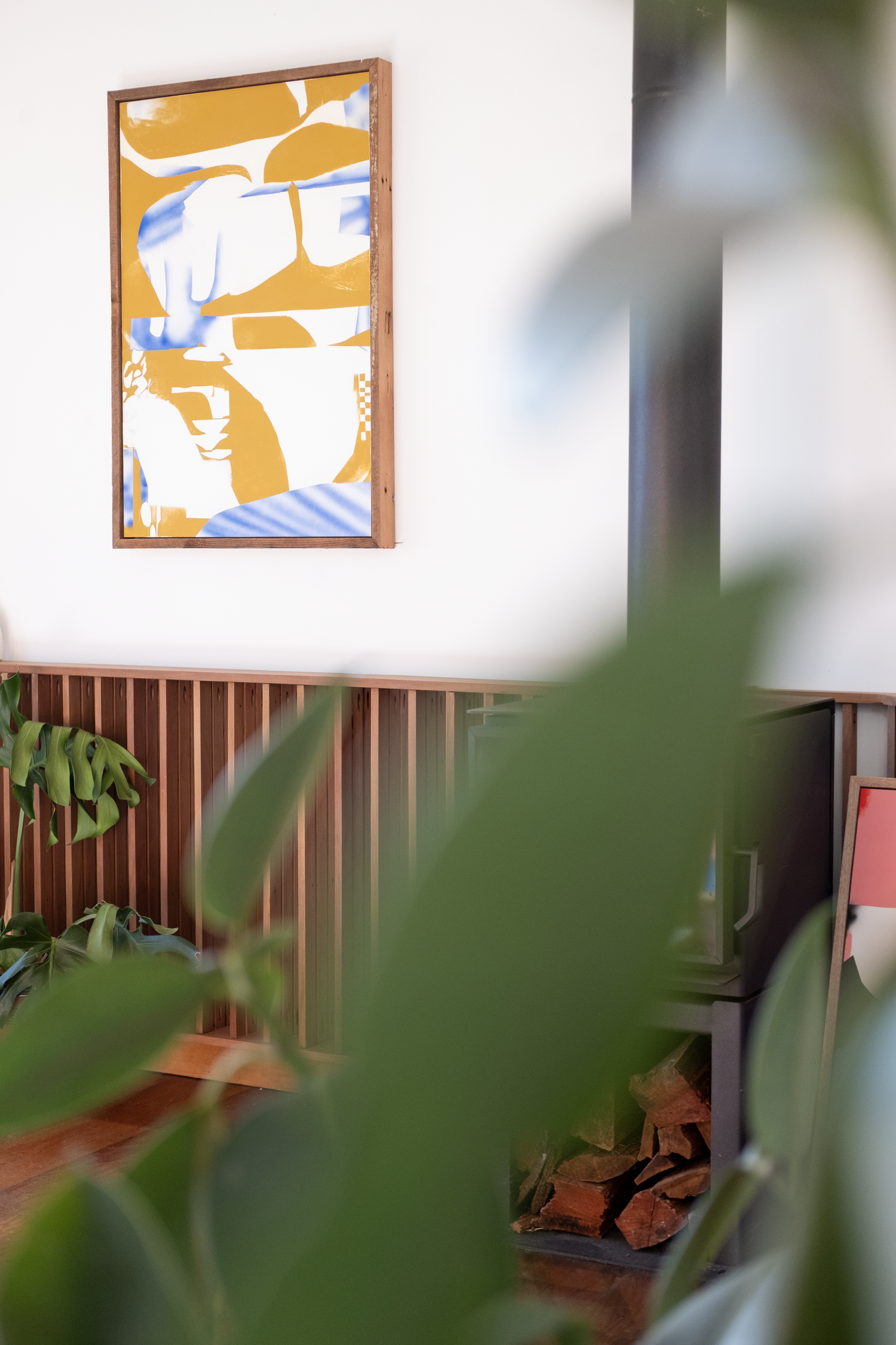 Living room with a colorful abstract painting on the wall, plants, and furniture.