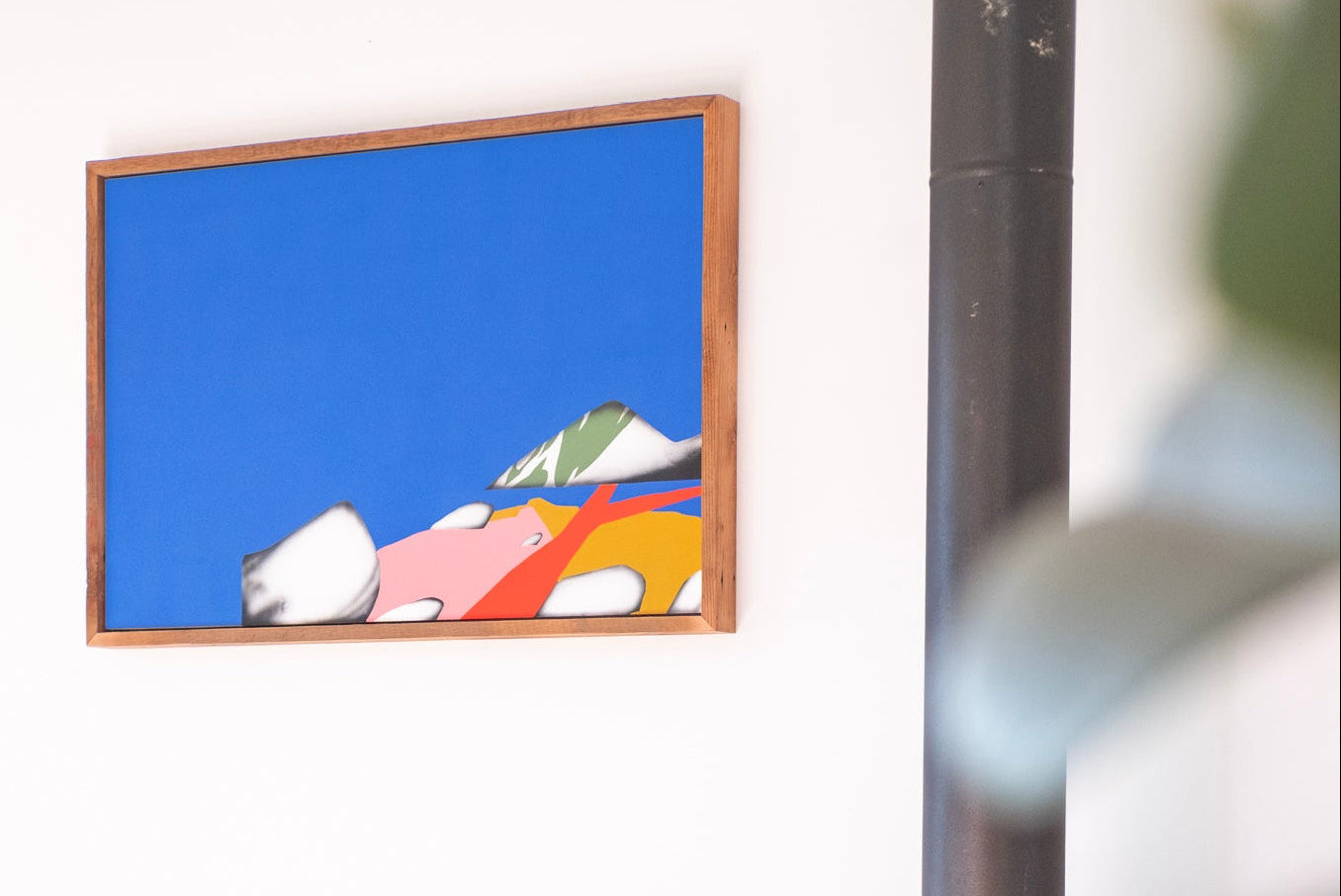 Colorful abstract painting on a wall with plants and a wooden panel in the foreground