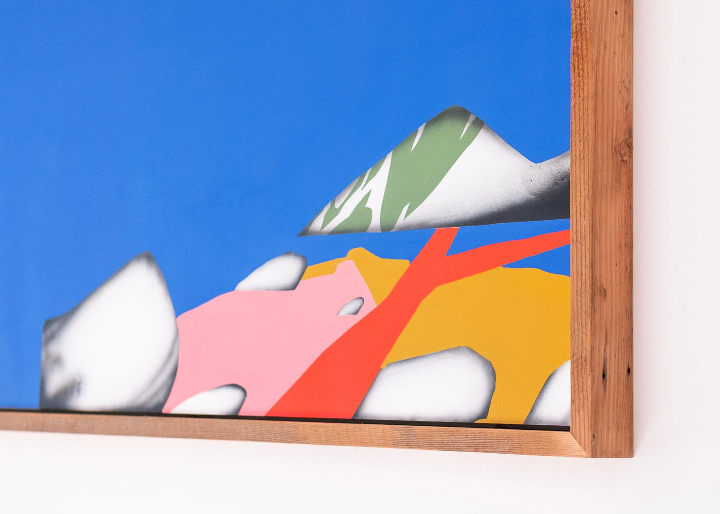 Colorful abstract painting with a wooden frame on a white wall